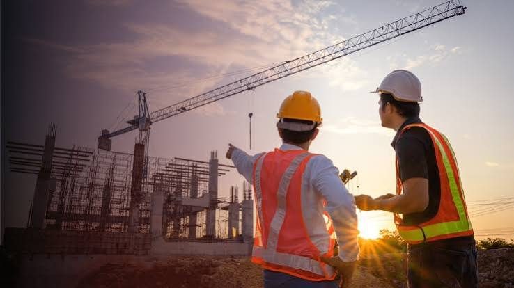Two site managers reviewing a construction project at sunset